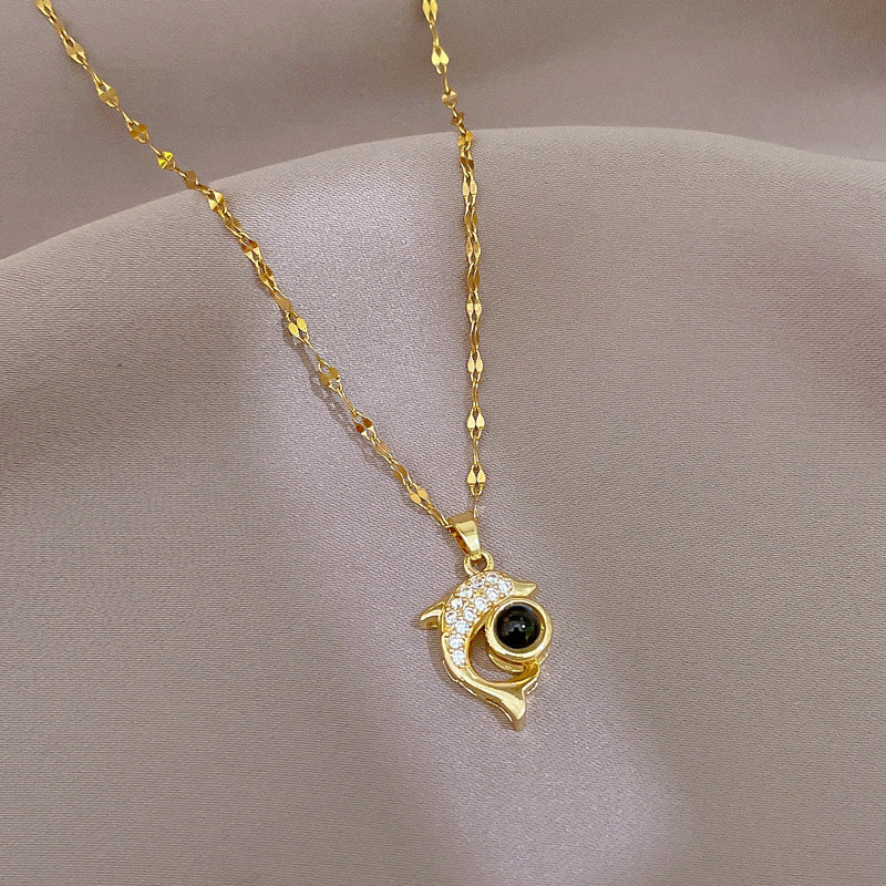 Collier dauphin femme en métal doré avec pendentif dauphin orné de pierres et pierre noire