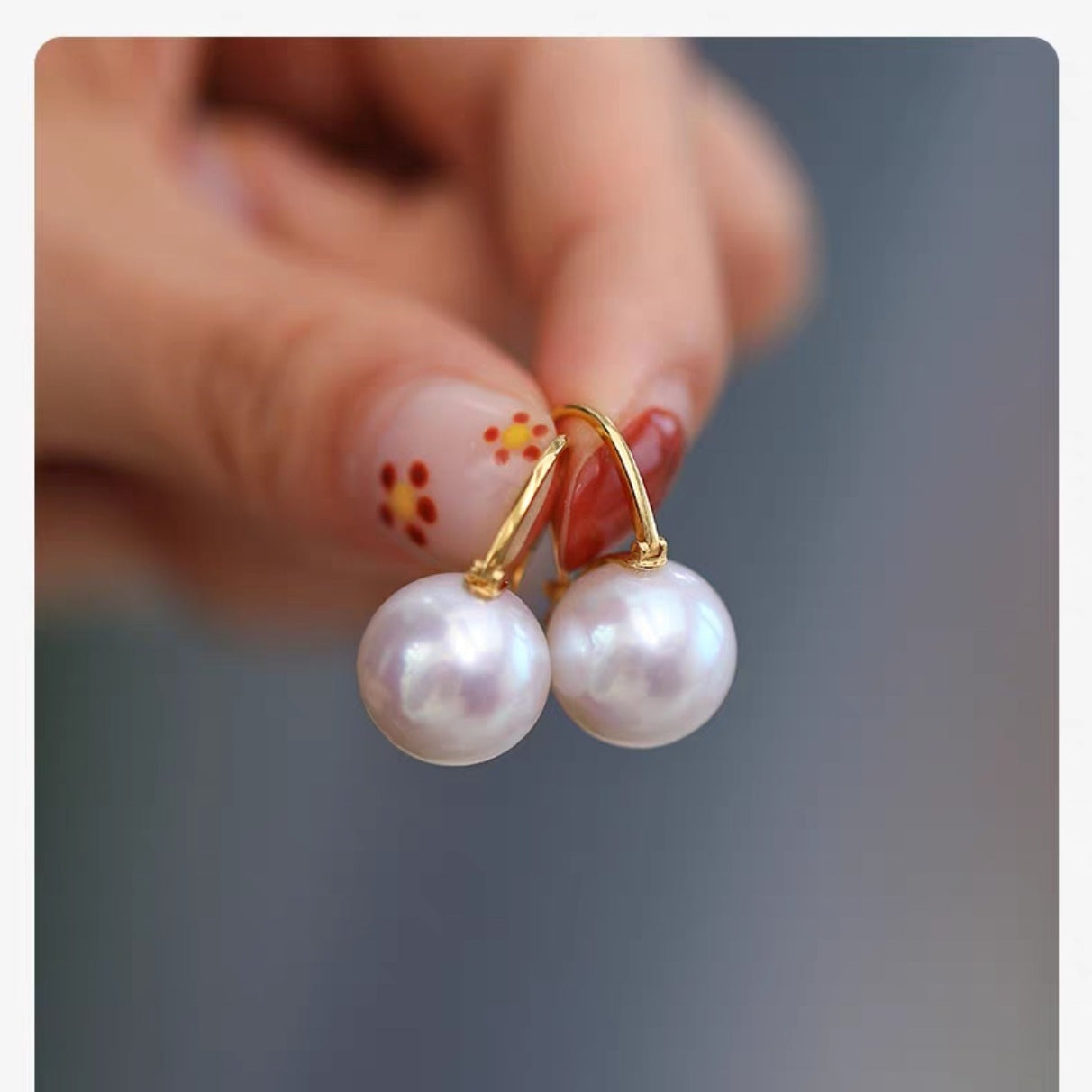 Boucles d'oreilles élégantes Moyyudé avec perles blanches et crochets dorés tenues par une main