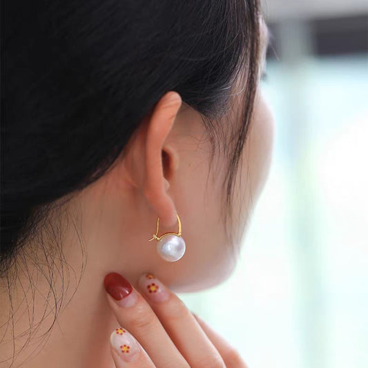 Boucles d'oreilles élégantes Moyyudé avec perle blanche et monture dorée portées par une femme