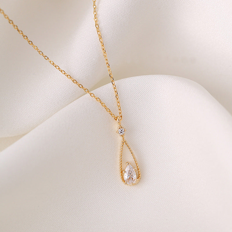 Collier goutte d'eau zircon doré elegant de Moyyudé sur fond en tissu blanc