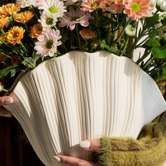 Vase en céramique fait main Moyyudé blanc avec texture ondulée tenu devant des fleurs colorées